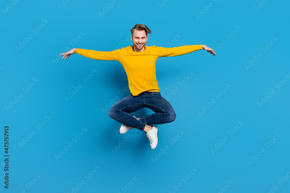 Full length body size of young guy jumping up cheerful funny childish playful isolated bright blue color background
