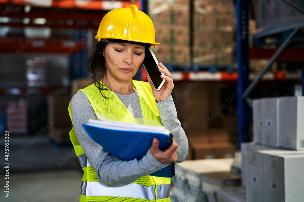 Adult caucasian woman talking by mobile phone in warehouse Adult caucasian woman talking by mobile phone in warehouse