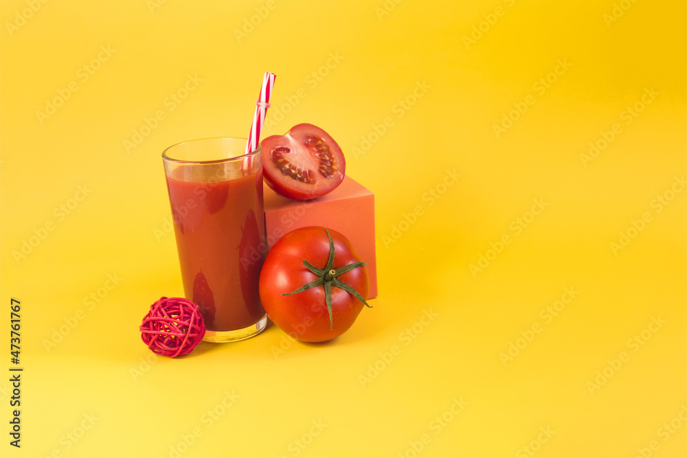 Natural tomato juice in a glass container with a decor of tomatoes, salt and a colored cube on a bright yellow background Natural tomato juice in a glass container with a decor of tomatoes, salt and a colored cube on a bright yellow background