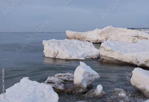 Winter Baltic Sea in Zelenogradsk Kaliningrad region. The sea is frozen over  there are many snow blocks. Seagulls fly over the icy breakwaters. People walk on the frozen sea.