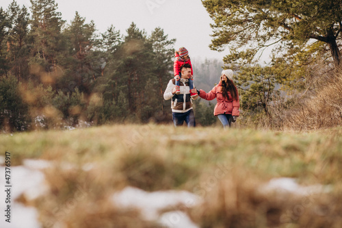 Young family together walking in forest at winter time
