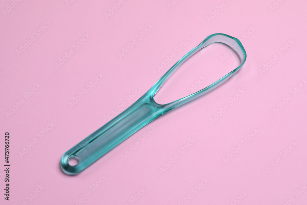 One turquoise tongue cleaner on pink background One turquoise tongue cleaner on pink background