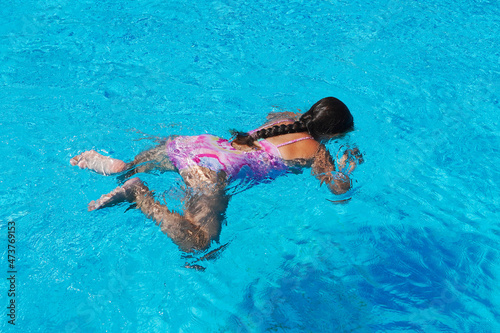  Little girl at swimming pool. Smiling Girl having fun in swimming pool on summer vacation. Swimming girl.