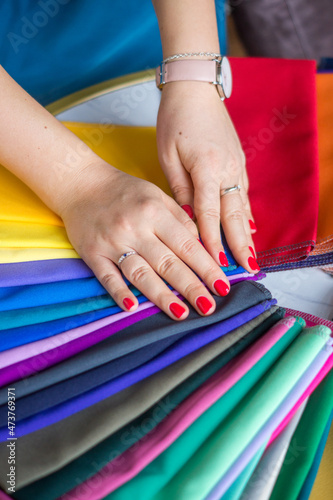  Hands of a girl on colored fabrics, scarves, tools for the work of a stylist, to determine the color type of appearance