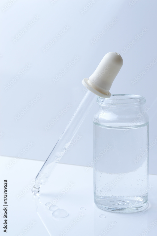 glass transparent jar and a cosmetic pipette with liquid droplets on a white background. glass transparent jar and a cosmetic pipette with liquid droplets on a white background.