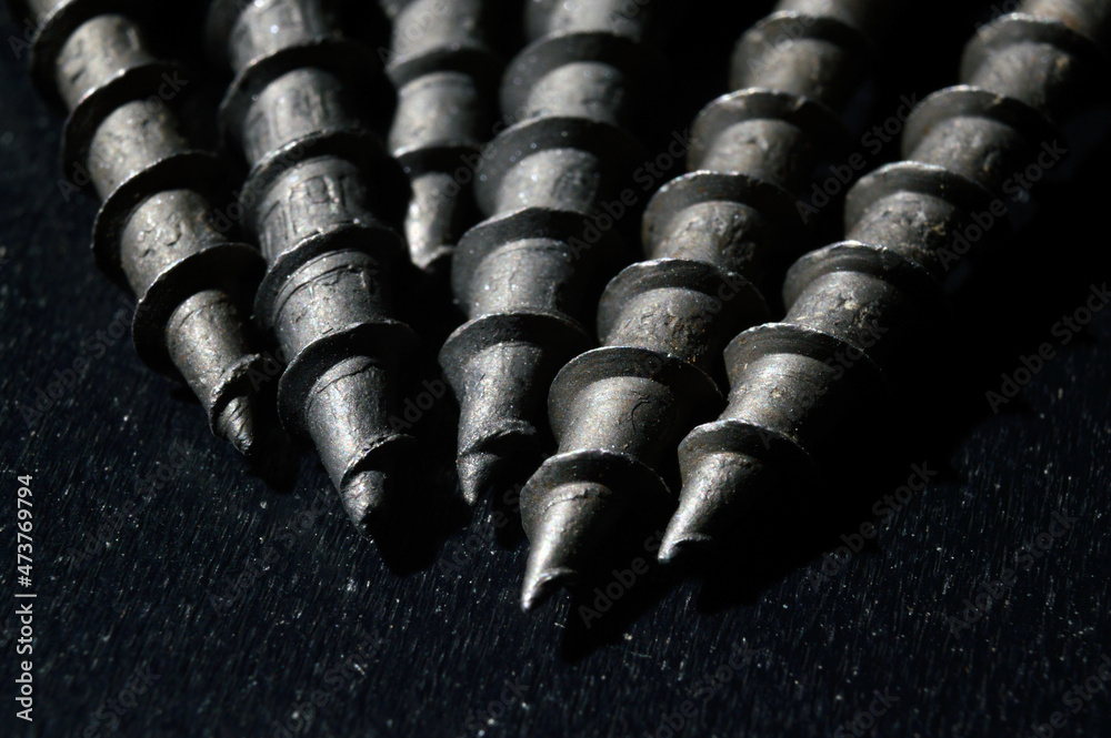 black hardened self-tapping screws lies on a dark background. close-up. black hardened self-tapping screws lies on a dark background. close-up.