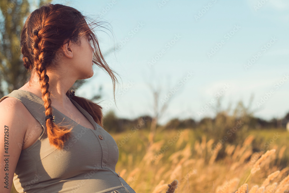 Obraz premium young beautiful pregnant woman looking ahead in field, relaxation on summer nature, preparation for childbirth, happy healthy motherhood