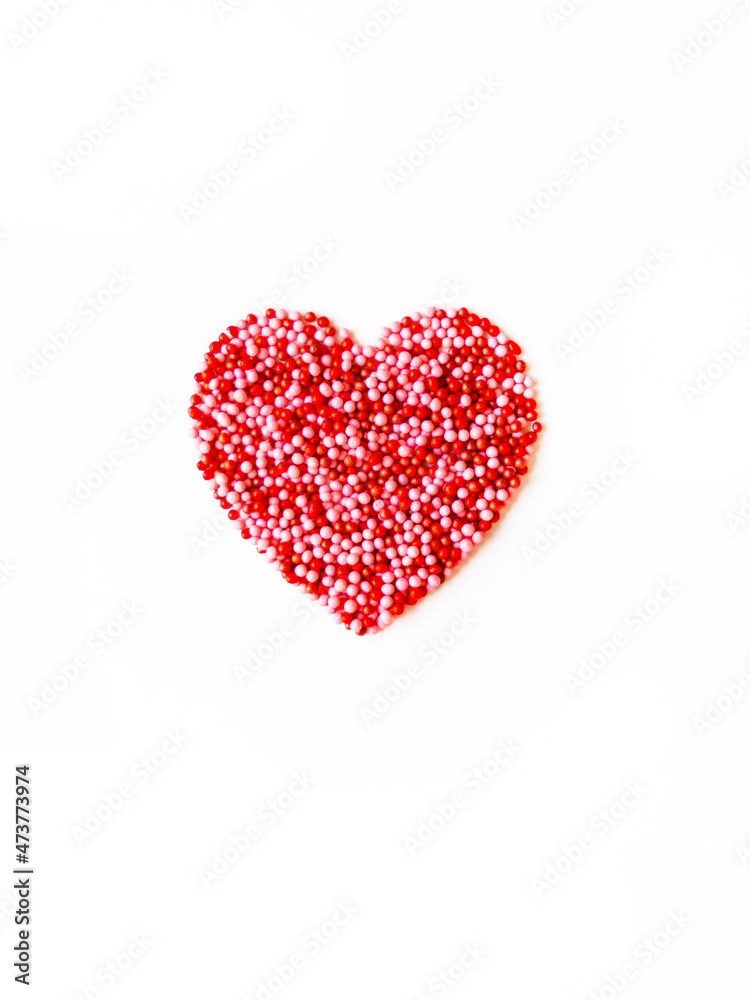 Valentine's card. Love heart made of red and pink pastry sprinkles on white background.