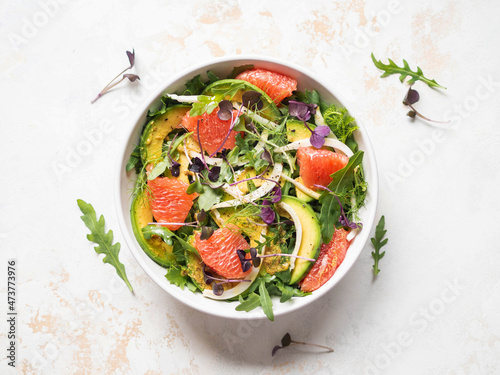Grapefruit, avocado, arugula, sprouts and fennel salad in white bowl.