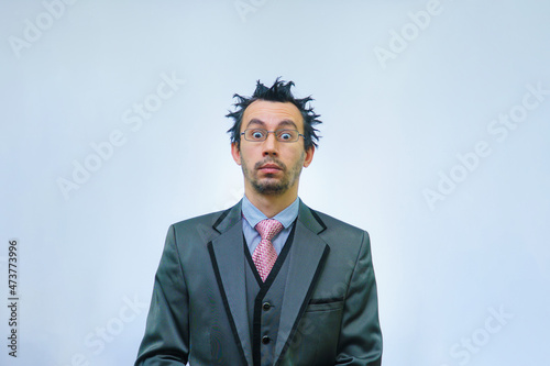 Shocked businessman with tousled hair looks into the camera.