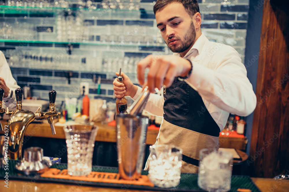 Handsome bartender making drinking and cocktails at a counter