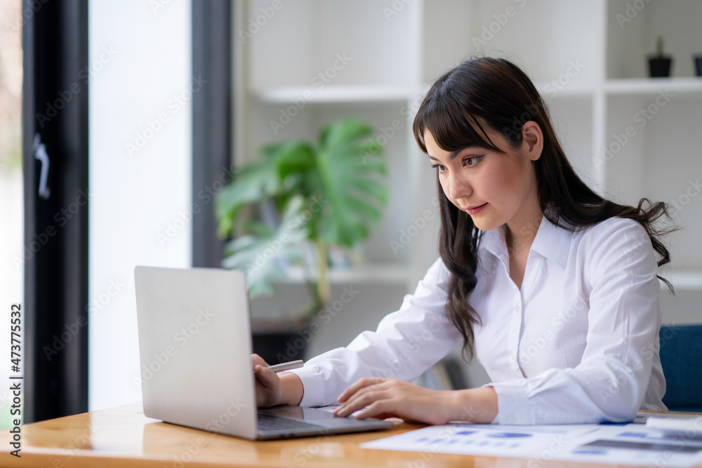 Portrait of a businesswoman typing on laptop preparing report analyzing work results, female executive doing paperwork at the workplace using a computer online for data Portrait of a businesswoman typing on laptop preparing report analyzing work results, female executive doing paperwork at the workplace using a computer online for data