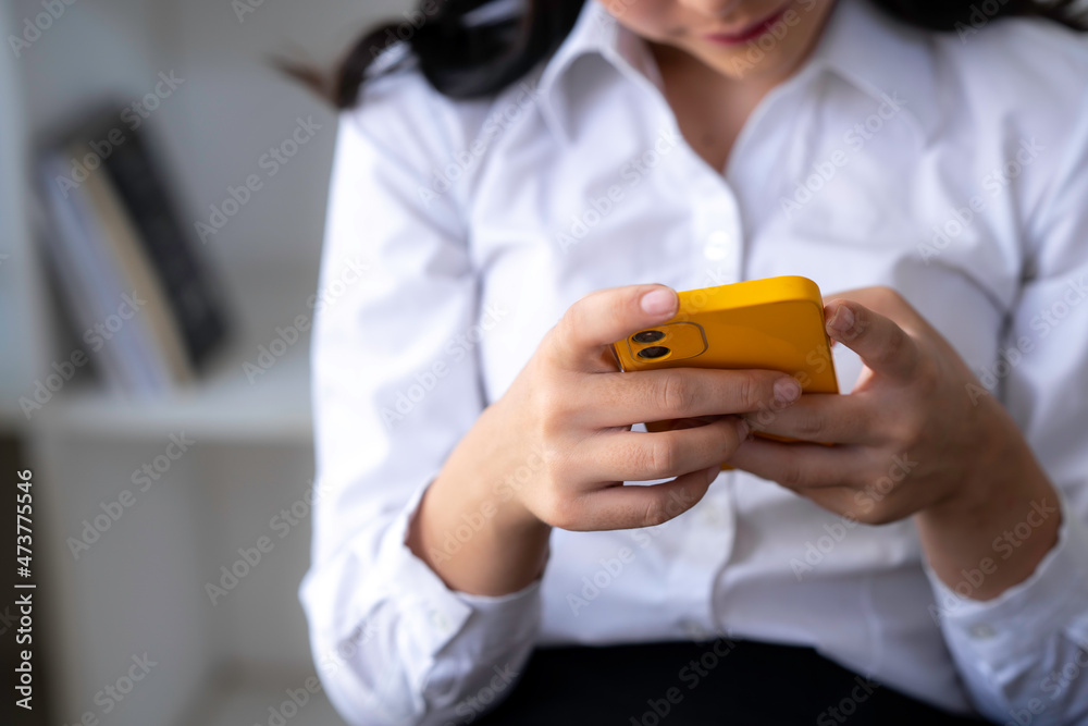 Smiling businesswoman using phone in office. Small business entrepreneur looking at her mobile phone