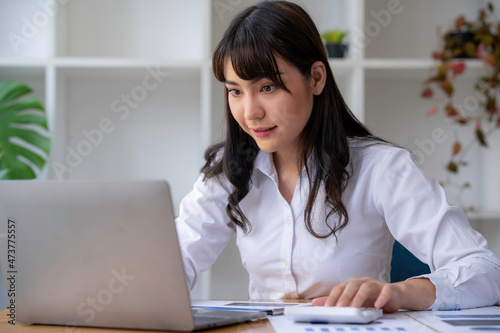 Portrait of a Business accounting concept, Businesswoman using a calculator with computer laptop, budget, and loan paper in the office.