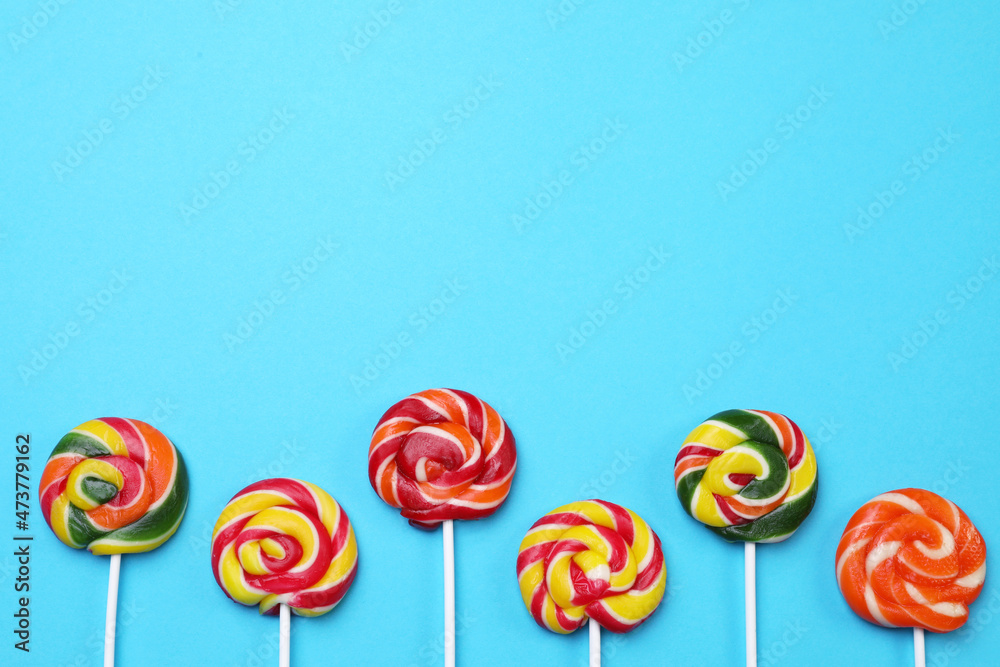 Sweet lollipops on light blue background, flat lay. Space for text