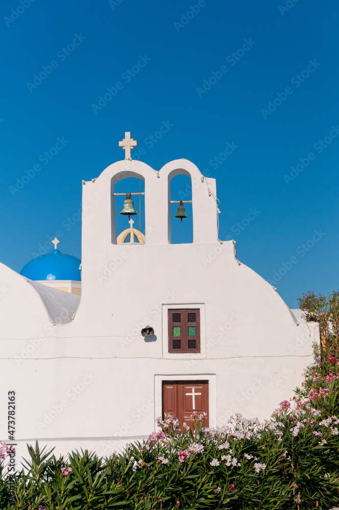 The front facade of a white-walled church against the blue sky in Santorini, Greece.