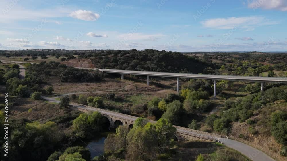 Aerial forward over old roman bridge and modern elevated road in background, Vila Formosa in Portugal