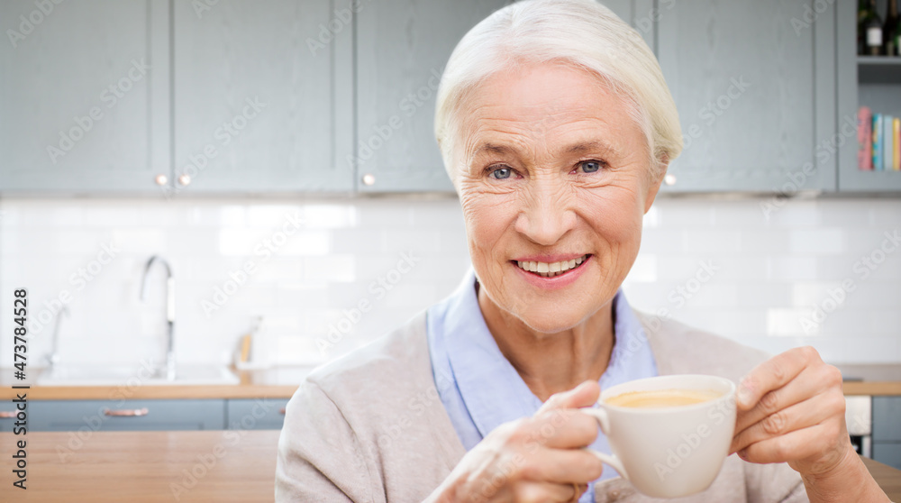 leisure and people concept - happy smiling senior woman with cup of coffee at home over kitchen background