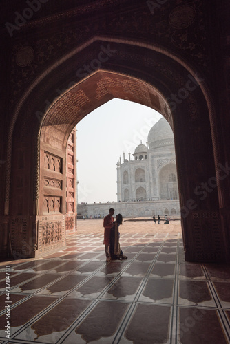 Romantic Couple near Taj Mahal. View in black arch silhouette from the mosque in Agra, Uttar Pradesh, India © gekkon4ik