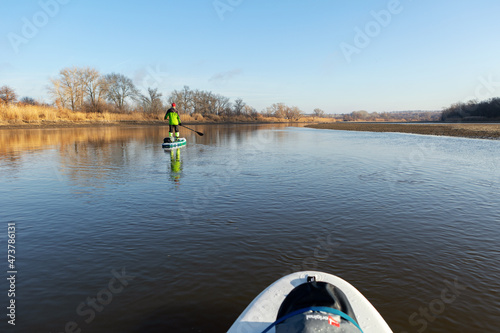 Late autumn on a clear day a man is rafting on a supboard on the river. SUP. Stand up paddle boarding