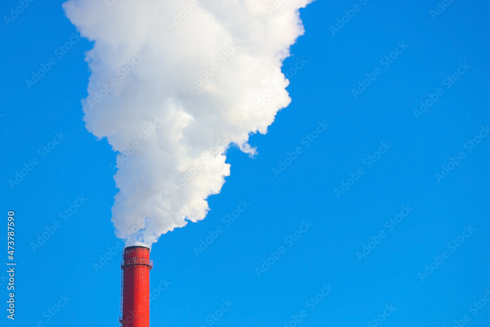 Smoke is coming from a red chimney against a blue sky Smoke is coming from a red chimney against a blue sky