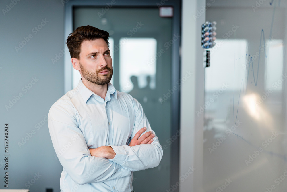 Businessman examining graph on whiteboard while working at office Businessman examining graph on whiteboard while working at office