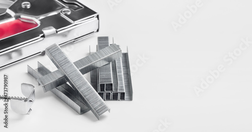 Stack of metal staples for stapler gun on light grey background, close up, copy space. Industrial tool.