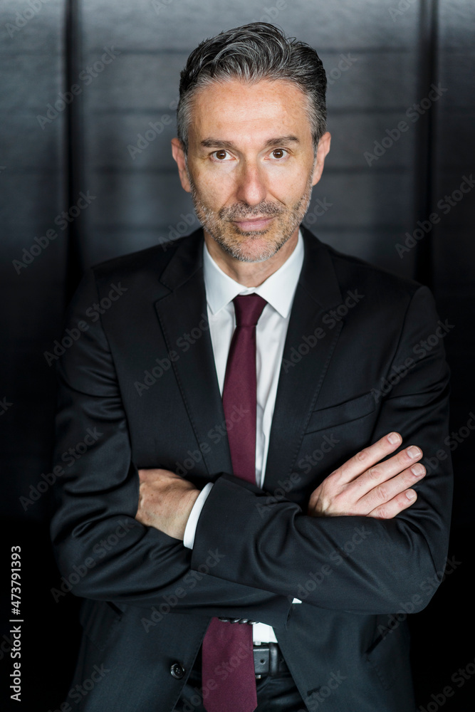 Mature businessman standing with arms crossed in office Mature businessman standing with arms crossed in office