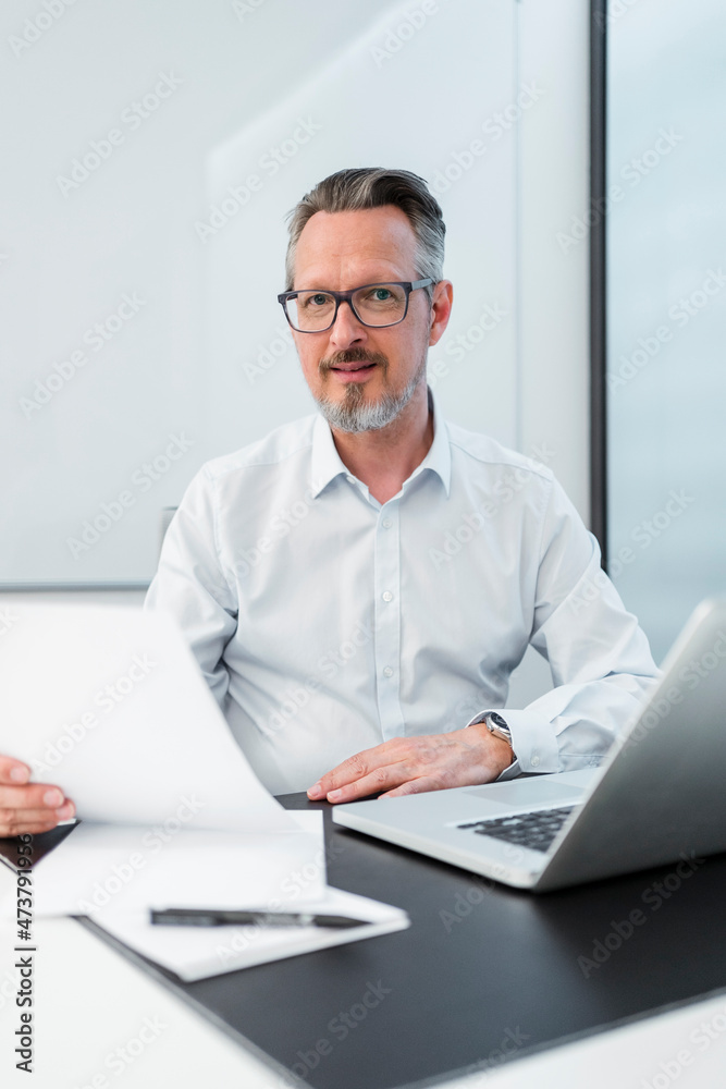 Male entrepreneur with laptop and document at office Male entrepreneur with laptop and document at office