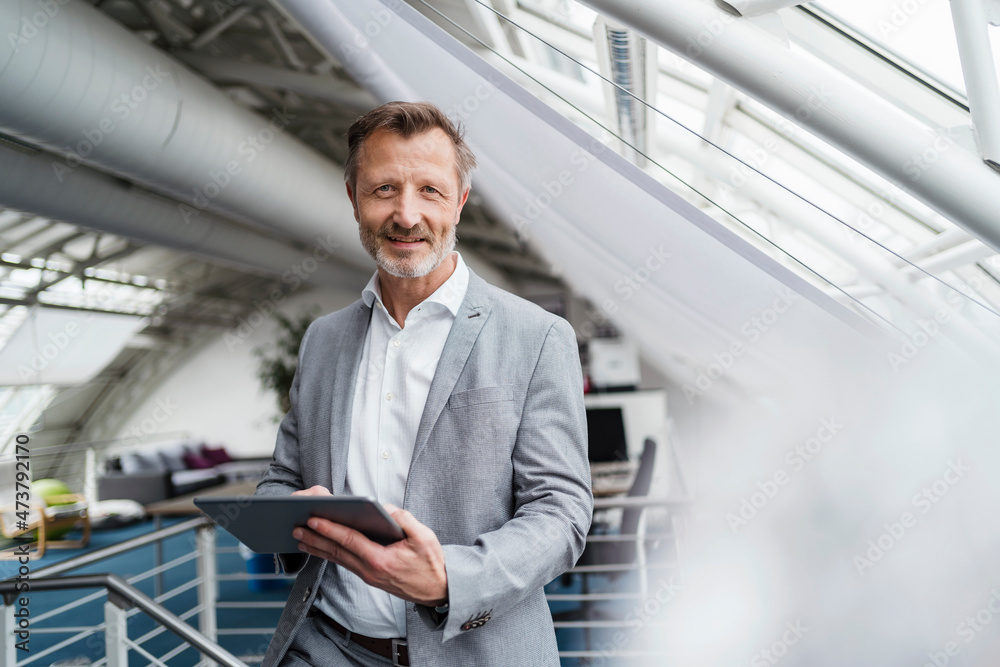 Businessman holding digital tablet while standing in office Businessman holding digital tablet while standing in office