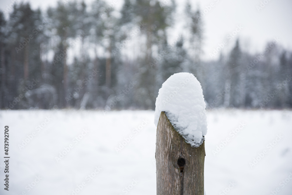 A hat made of snow on a lonely wooden post
