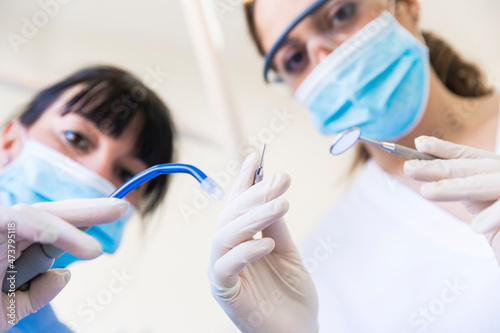 Female dentist with assistant holding dental equipment at clinic photo
