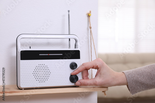 Fototapeta Naklejka Na Ścianę i Meble -  Woman turning volume knob on radio at home, closeup