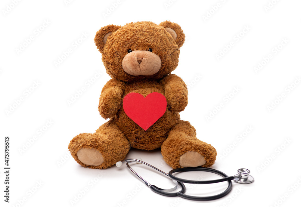 Obraz premium medicine, healthcare and childhood concept - teddy bear toy with stethoscope holding red heart on white background