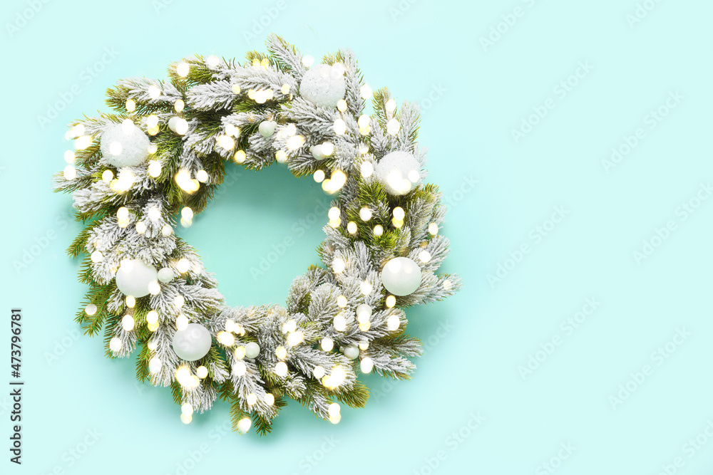 Christmas wreath with white baubles, snowy branches and garland on blue background. Xmas greeting card. Top view. Traditional decoration for festive holiday in luxury modern style with gold potal.