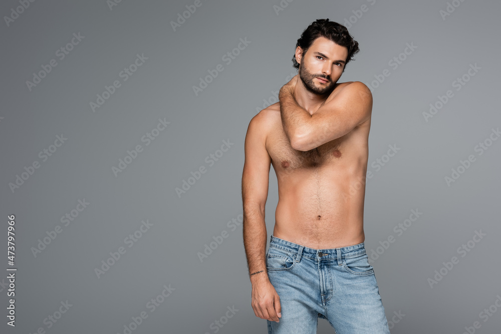 good-looking and muscular man in jeans looking at camera isolated on grey good-looking and muscular man in jeans looking at camera isolated on grey