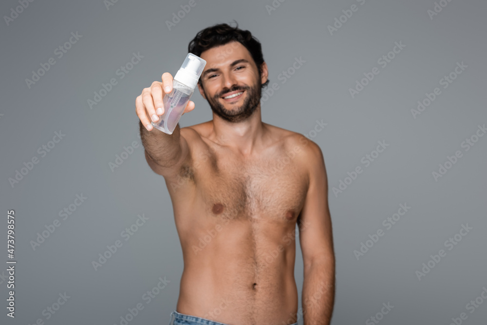 Fototapeta premium happy and shirtless man holding foam cleanser isolated on grey