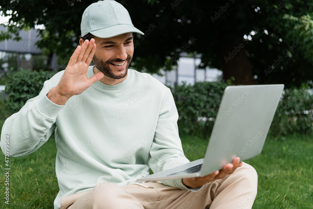 joyful man waving hand during video call in park joyful man waving hand during video call in park