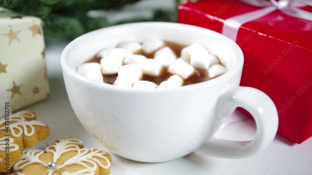 Adding marshmallow in hot chocolate close-up video, on Christmas tree and gift boxes background Adding marshmallow in hot chocolate close-up video, on Christmas tree and gift boxes background