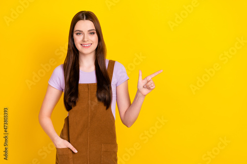 Portrait of attractive cheerful brown-haired girl demonstrating copy space isolated over bright yellow color background © deagreez