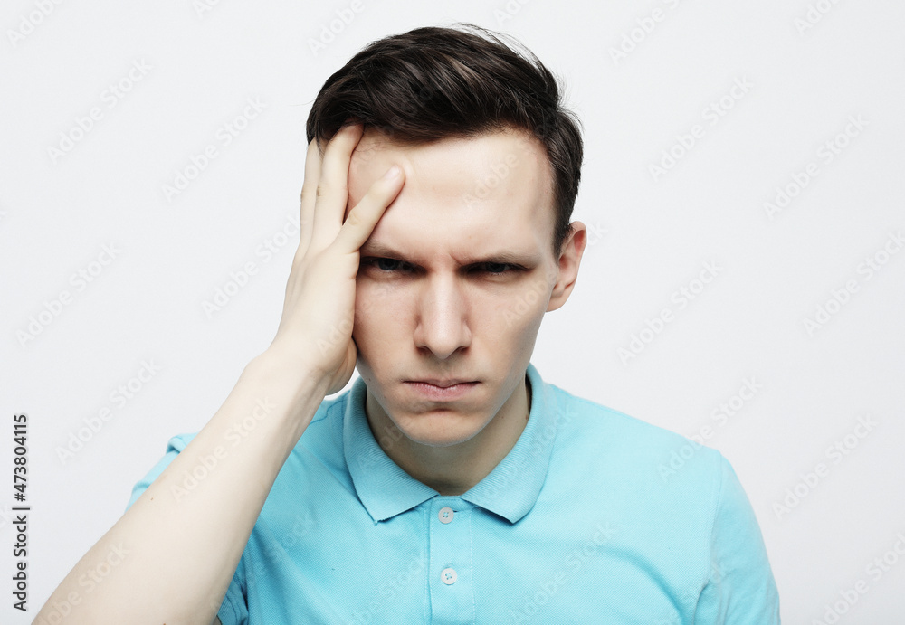 Stressed upset man suffering from a strong migraine isolated over white gray background