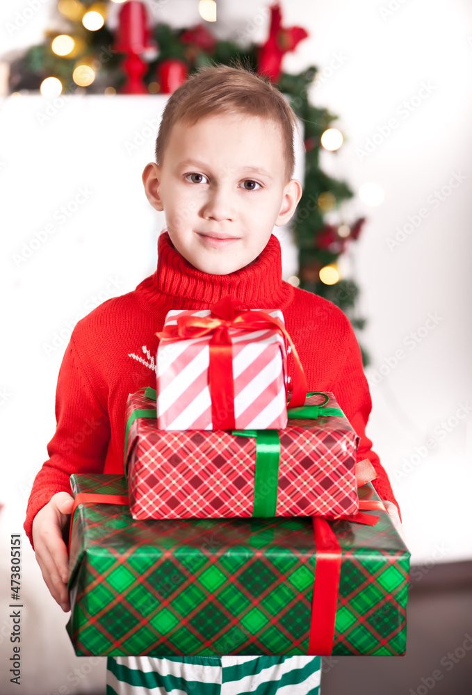 Child boy kid in red knitted sweater holding a Christmas gift boxes in a hands Child boy kid in red knitted sweater holding a Christmas gift boxes in a hands