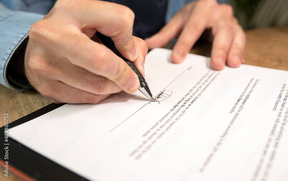 Male professional doing signature on document in office Male professional doing signature on document in office