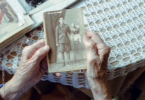 Senior woman remembering past while watching old photograph at home photo