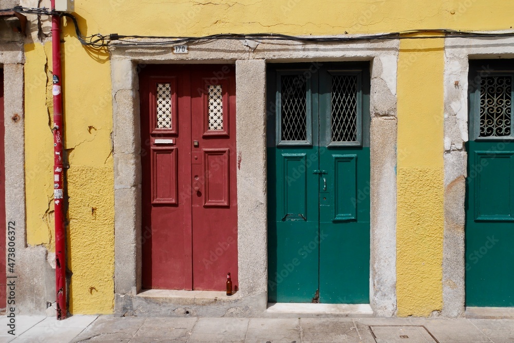 Close up of yellow house facade with red and green entrance doors in old town of Porto, Portugal.