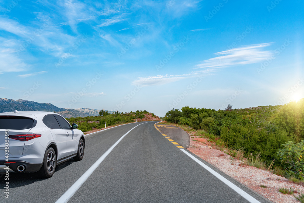 White car on a scenic road. Car on the road surrounded by a magnificent natural landscape. White car on a scenic road. Car on the road surrounded by a magnificent natural landscape.