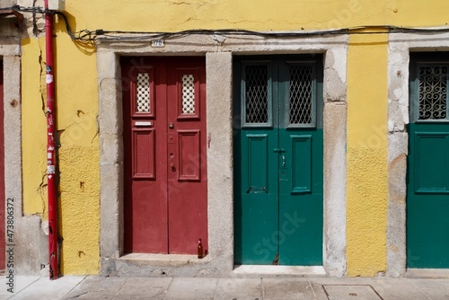 Close up of yellow house facade with red and green entrance doors in old town of Porto, Portugal. © Maleo Photography