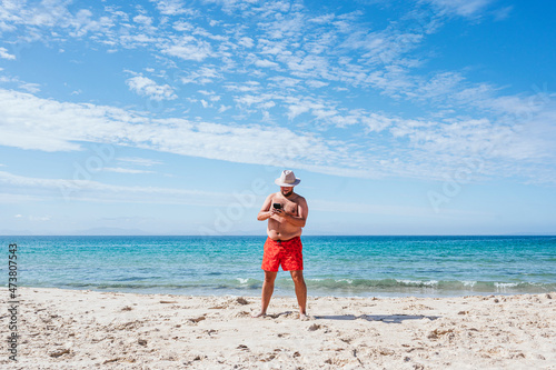 Wallpaper Mural Shirtless gay man using mobile phone at beach during vacation Torontodigital.ca