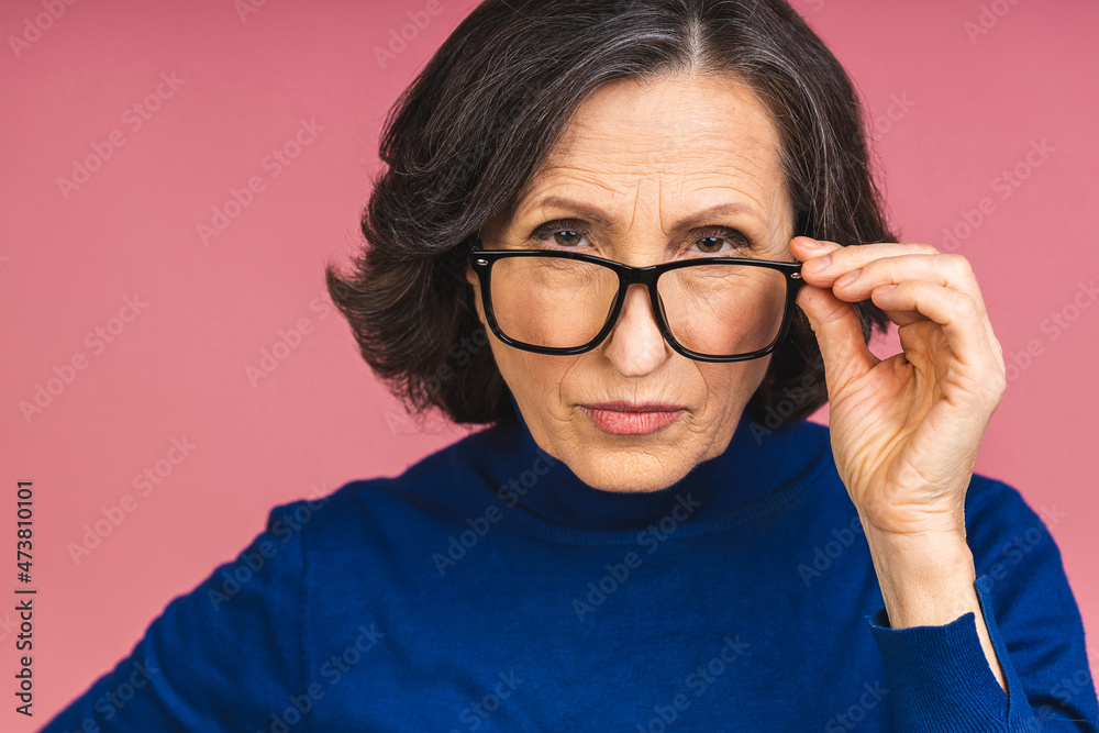 Mature senior aged serious or angry old woman isolated over pink background. Mature senior aged serious or angry old woman isolated over pink background.