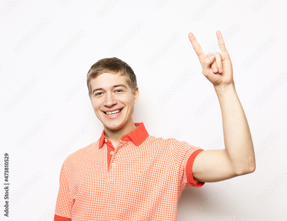 Happy young handsome man gesturing and keeping mouth open while standing against white background